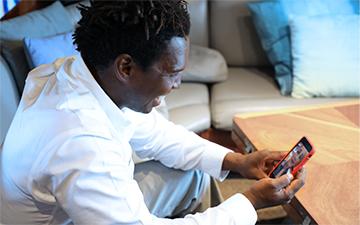 一名男子坐在一艘超级游艇内，用智能手机进行游艇互联网视频聊天.